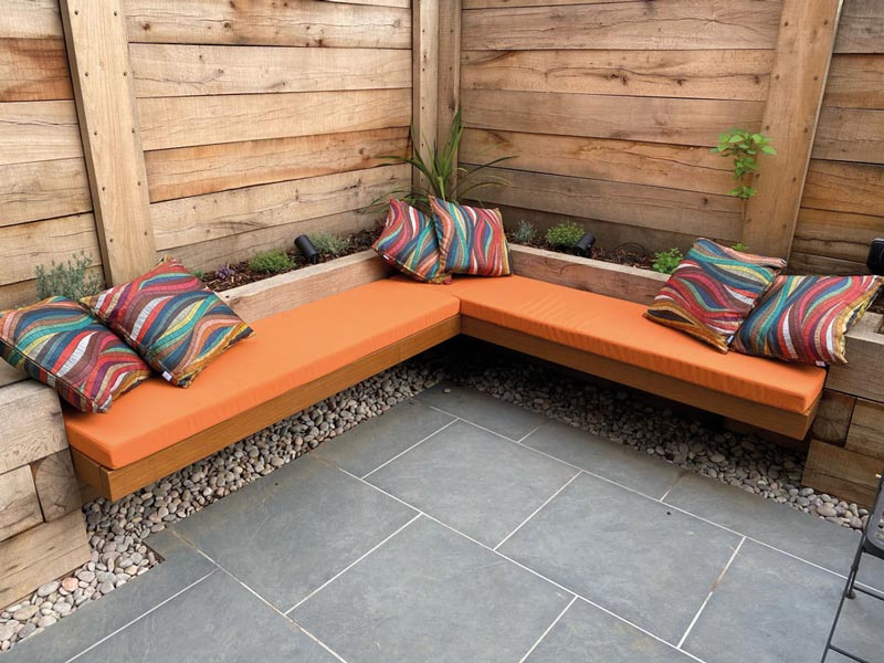 Outdoor seat and scatter cushions copmplement this railway sleeper garden seating area