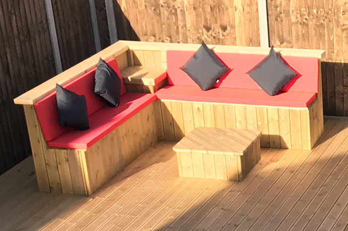 Outdoor foam filled seat cushions for a bespoke corner seating area built from decking wood.